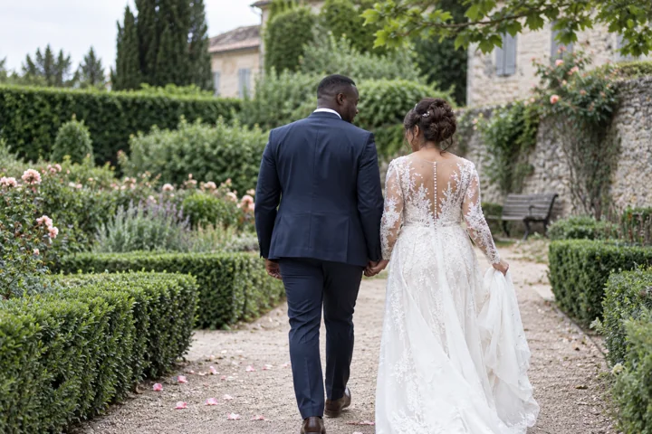 Un couple de mariés vu de dos dans un jardin